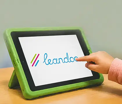 Kind tippt auf ein Tablet mit dem Leandoo-Logo.